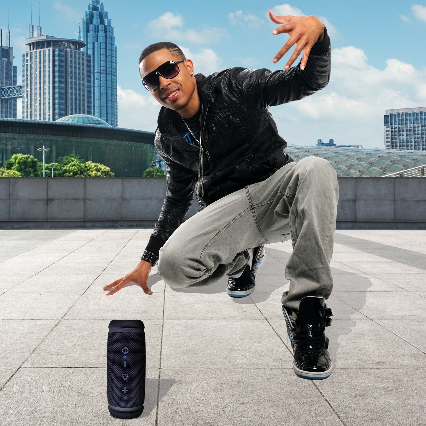 Young African American man with the Sound Stage Speaker in the foreground and a cityscape in the background.
