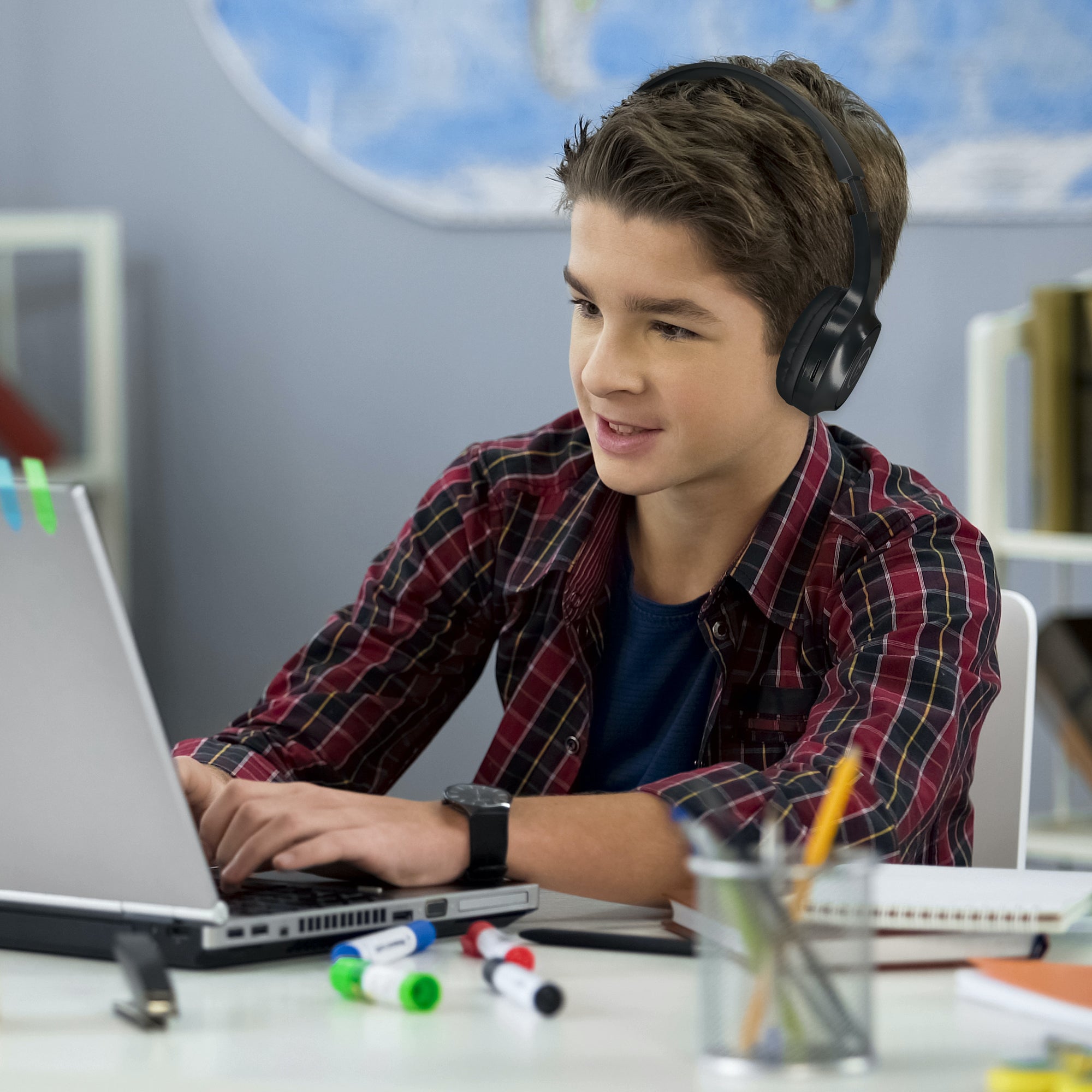 Photo of Morpheus 360 Tremors Wireless on-ear Headphones show a young child wearing the headphones while attending online school from his laptop.